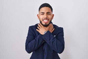 Young hispanic man wearing business suit and tie shouting suffocate because painful strangle. health problem. asphyxiate and suicide concept.