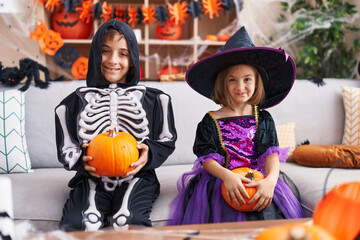 Obraz na płótnie Canvas Adorable boy and girl having halloween party holding pumpkin at home