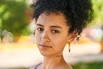 Young hispanic woman with relaxed expression standing at park