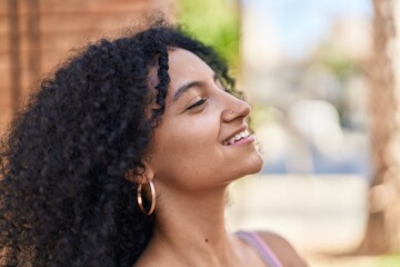 Young hispanic woman smiling confident breathing at street