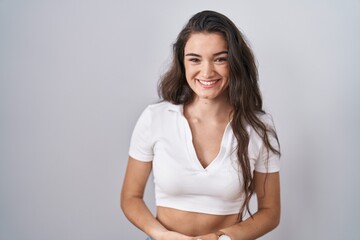 Fototapeta premium Young teenager girl standing over white background with hands together and crossed fingers smiling relaxed and cheerful. success and optimistic