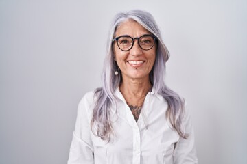 Middle age woman with tattoos wearing glasses standing over white background with a happy and cool smile on face. lucky person.