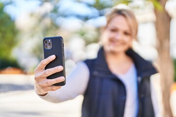 Young blonde woman smiling confident making selfie by the smartphone at park