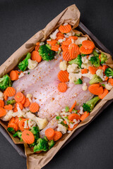 Raw sea bass fish fillet with salt, spices and vegetables in a baking dish