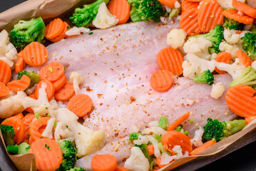 Raw sea bass fish fillet with salt, spices and vegetables in a baking dish