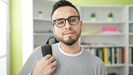 Hispanic man student wearing glasses and backpack at library university