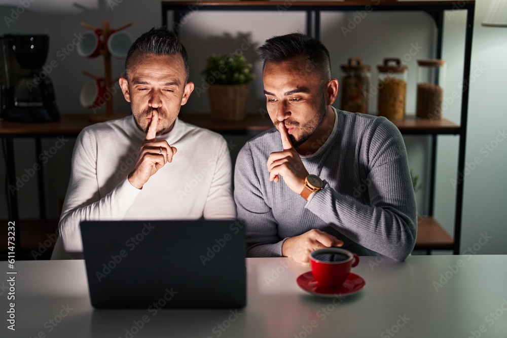 Wall mural homosexual couple using computer laptop asking to be quiet with finger on lips. silence and secret c