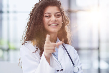 Fototapeta na wymiar Portrait of an attractive young female doctor in a white coat points her finger