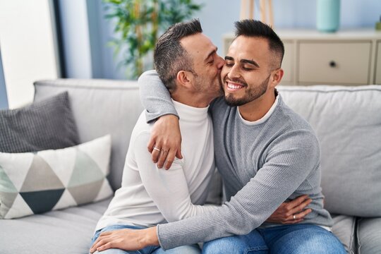 Two men couple hugging each other kissing at home
