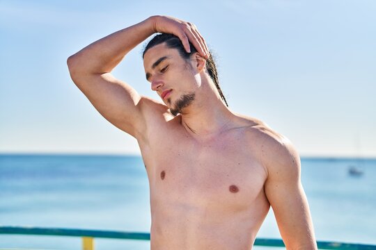 Young man stretching neck at seaside