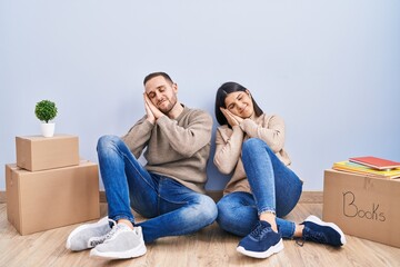 Young couple moving to a new home sleeping tired dreaming and posing with hands together while smiling with closed eyes.