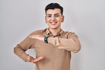 Non binary person standing over isolated background gesturing with hands showing big and large size sign, measure symbol. smiling looking at the camera. measuring concept.