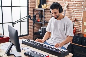 Young arab man musician playing piano keyboard at music studio - obrazy, fototapety, plakaty