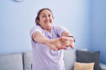 Senior woman smiling confident stretching arms at home