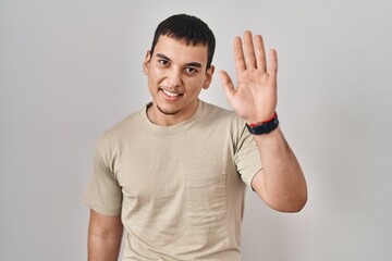 Young arab man wearing casual t shirt waiving saying hello happy and smiling, friendly welcome...