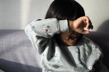 a upset child girl cover her face with hand 