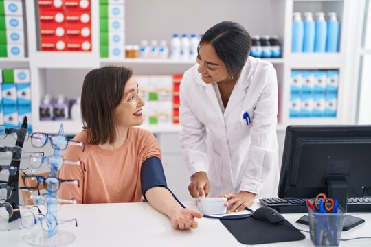 Two women pharmacist and customer measuring blood pressure at pharmacy