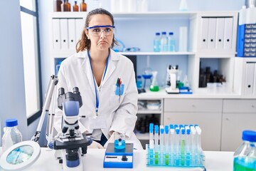 Fototapeta premium Young hispanic woman working at scientist laboratory depressed and worry for distress, crying angry and afraid. sad expression.