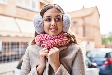 Young beautiful hispanic woman smiling confident wearing scarf and earmuff at street