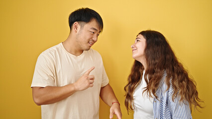 Man and woman couple standing speaking over isolated yellow background