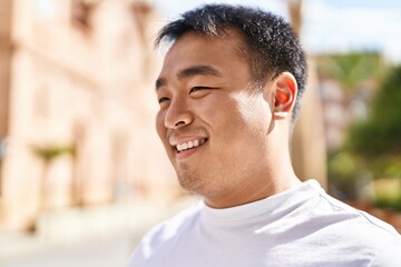 Young chinese man smiling confident standing at street