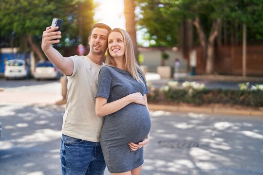 Man and woman couple expecting baby make selfie by smartphone at street