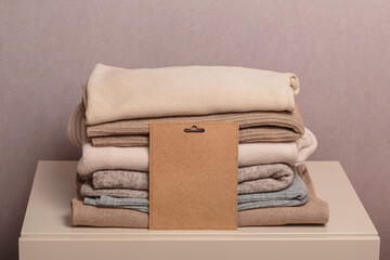 Stack of second hand clothes with used wardrobe for reuse and empty craft card. Circular fashion,...