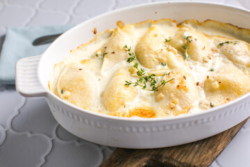 cheesy and creamy chicken and shells pasta bake in baking dish on dark grey concrete table,...