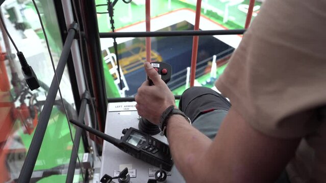 Crane operator inside cabin. Hand takes joystick and pull. Crane operator works