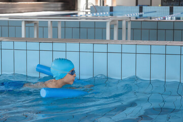Close up boy swimmer o school boy learning how to swim in a pool wearing in swimming cap and goggles