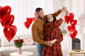 Lovely couple dancing in room decorated with heart shaped air balloons. Valentine's day celebration