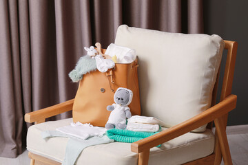 Mother's bag with baby's stuff on armchair indoors