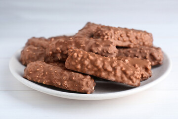 Tasty sweet chocolate bars on white wooden table, closeup