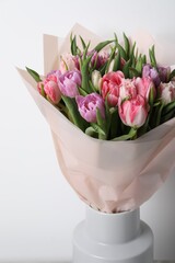 Vase with bouquet of beautiful tulips on white background, closeup