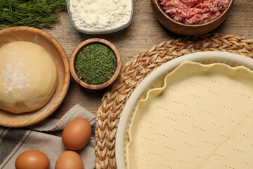 Flat lay composition with raw dough and ingredients on wooden table. Baking meat pie