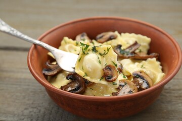 Delicious ravioli with mushrooms and fork on wooden table, closeup