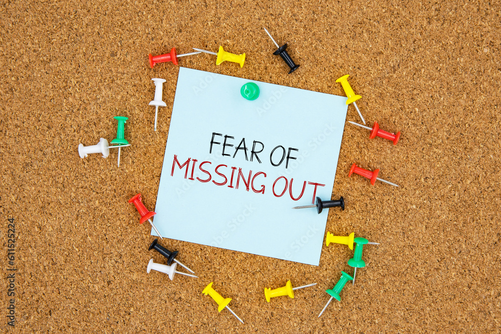 Poster fear of missing out text on light blue post-it paper pinned on bulletin cork board surrounding by mu