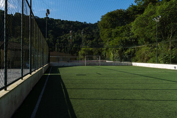 View of the society soccer field with nature around. Green synthetic grass and railings all around....
