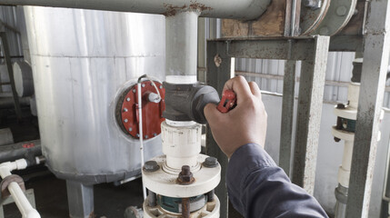 The mechanic turn the round valve on the pipe line boiler system in industry.