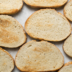 Top view of slice of toasted bread on a marble counter, slices of bread on a cutting bread, cut...