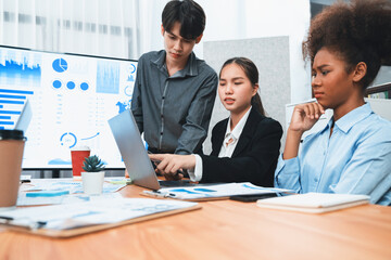 Diverse businesspeople analyzing financial dashboard data on laptop in serious meeting, confused...