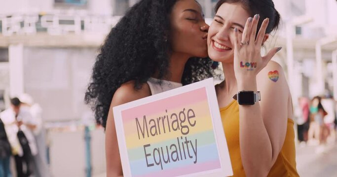 A lesbian couple with a rainbow tattoo sticker and flag representing the symbol of homosexuality in a pride parade