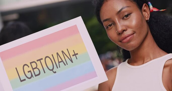 A young black woman with rainbow tattoo stickers and showing symbols of homosexuality in pride parade.