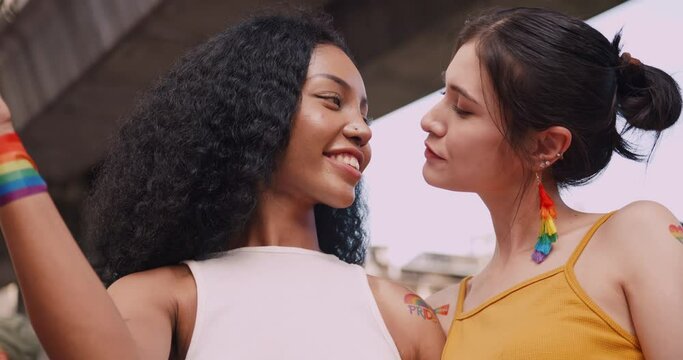 A lesbian couple with a rainbow tattoo sticker and flag representing the symbol of homosexuality in a pride parade