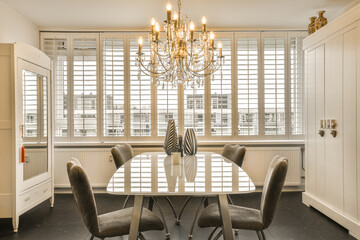 a dining room with several chairs and a chandel in the center of the room, there is a window that...