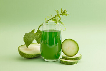 Front view of a glass of juice with fresh winter melon slices and leaf decorated on a light green...
