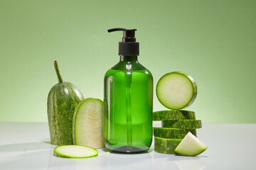 Front view of a green bottle unbranded with fresh winter melon slices displayed on green background. Mockup scene for advertising product, shampoo, shower gel or body lotion…with winter melon extract