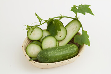 A beige basket containing slices of winter melon and leaf placed on white background. Advertising scene for product with winter melon ingredient.