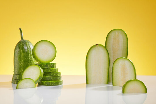 Minimal creative scene for advertising cosmetic of winter melon extract - fresh winter melon slices decorated on a yellow background. Blank space to place your product. Front view