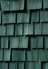 dark green wooden shingles on side of building square and rectangular shapes overlapping on wall vertical background backdrop or wallpaper dark green color on wood shadows from sun room for type 